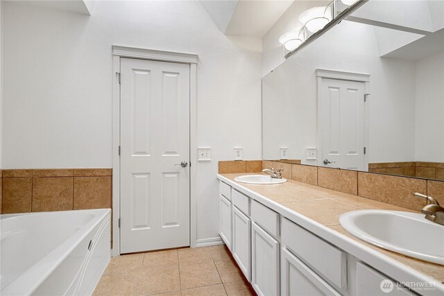 full bath featuring tile patterned flooring, double vanity, a tub, and a sink