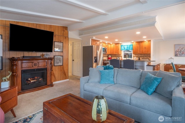 living area with light carpet, lofted ceiling with beams, a glass covered fireplace, recessed lighting, and baseboards