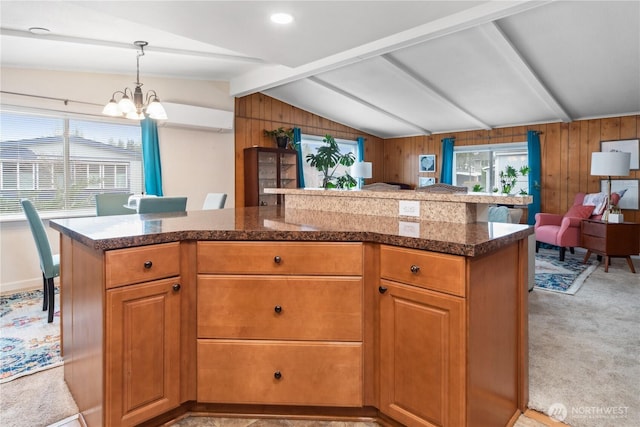 kitchen featuring wooden walls, vaulted ceiling with beams, pendant lighting, light carpet, and a notable chandelier