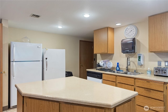 kitchen featuring visible vents, a sink, a center island, white appliances, and light countertops