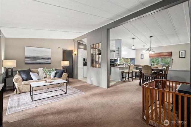 living room featuring a notable chandelier, vaulted ceiling with beams, and carpet