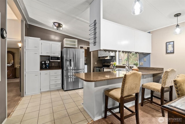 kitchen featuring a sink, dark countertops, stainless steel appliances, a peninsula, and light tile patterned floors