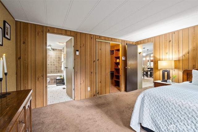 bedroom featuring a closet, ensuite bath, wood walls, and carpet flooring