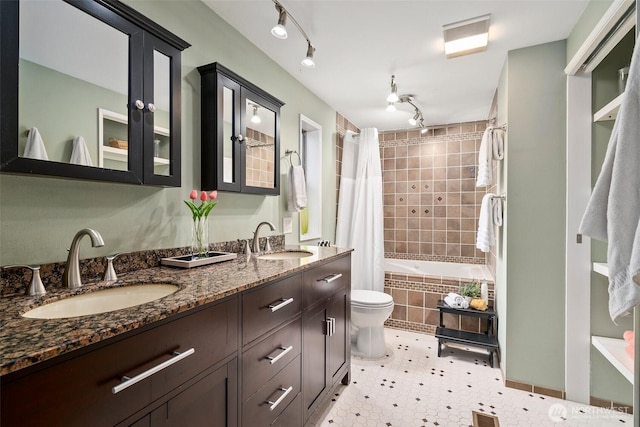 bathroom featuring double vanity, toilet, tiled shower / bath, and a sink