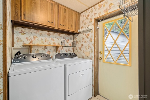 washroom featuring washer and clothes dryer, cabinet space, and wallpapered walls