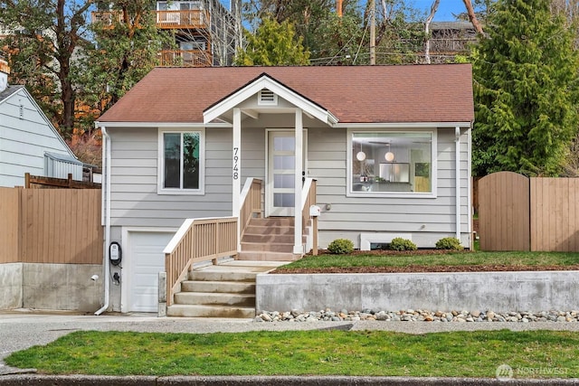 view of front facade with a garage, roof with shingles, and fence