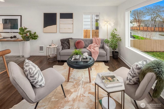 living area with visible vents, wood finished floors, and baseboards