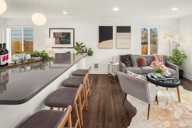 living room with recessed lighting, visible vents, baseboards, and wood finished floors