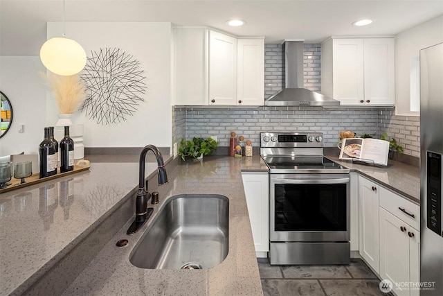 kitchen with white cabinets, appliances with stainless steel finishes, wall chimney exhaust hood, and a sink