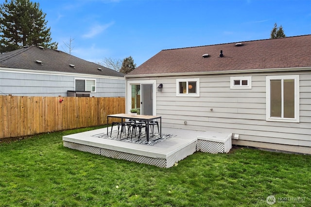 back of property with a shingled roof, a yard, fence, and a wooden deck