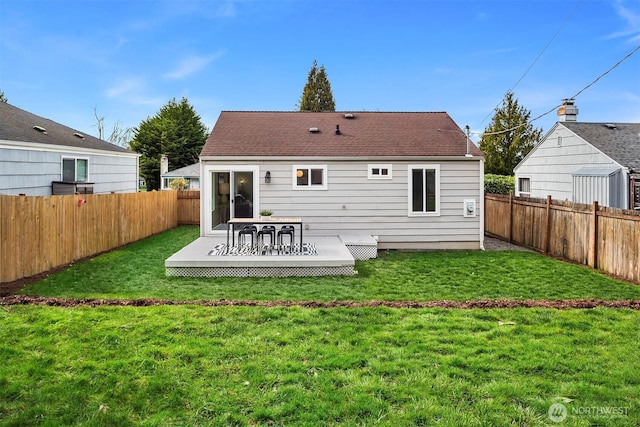 rear view of house featuring a deck, a lawn, and a fenced backyard