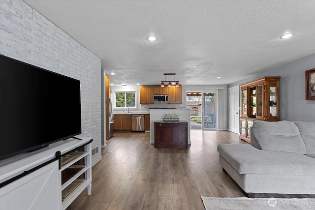 living room featuring visible vents, a healthy amount of sunlight, a textured ceiling, and light wood-type flooring