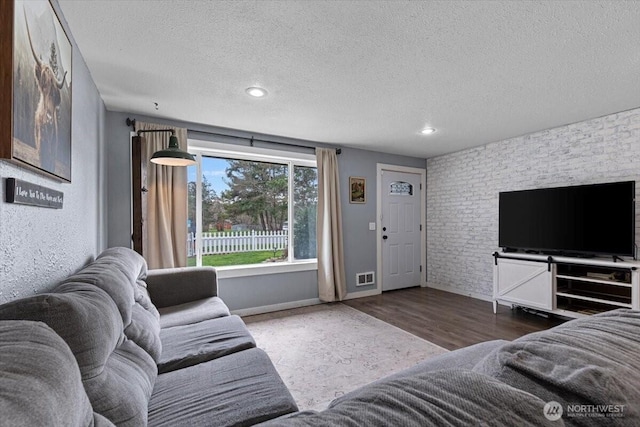 living area with wood finished floors, baseboards, visible vents, recessed lighting, and a textured ceiling