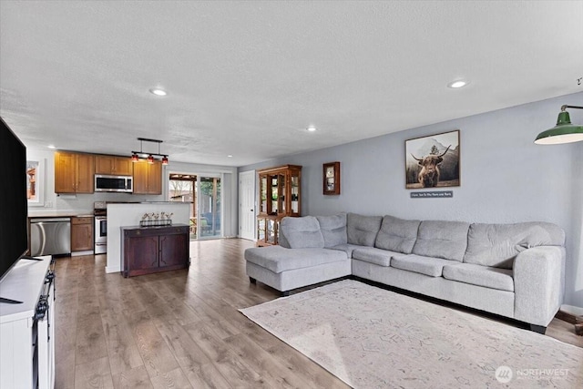 living area with light wood-style flooring, recessed lighting, and a textured ceiling