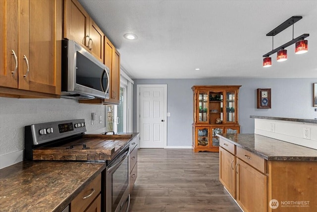 kitchen featuring brown cabinetry, baseboards, dark wood finished floors, recessed lighting, and appliances with stainless steel finishes