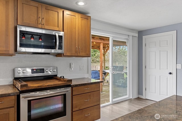 kitchen featuring brown cabinetry, light wood-style floors, appliances with stainless steel finishes, and a textured ceiling