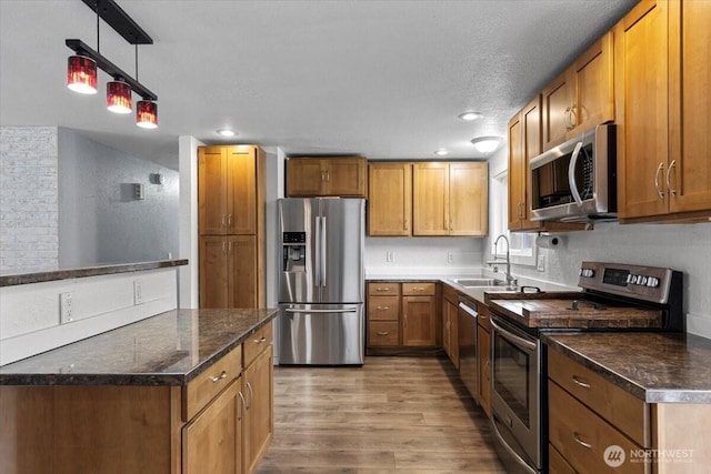 kitchen with a sink, brown cabinetry, light wood-style floors, and stainless steel appliances