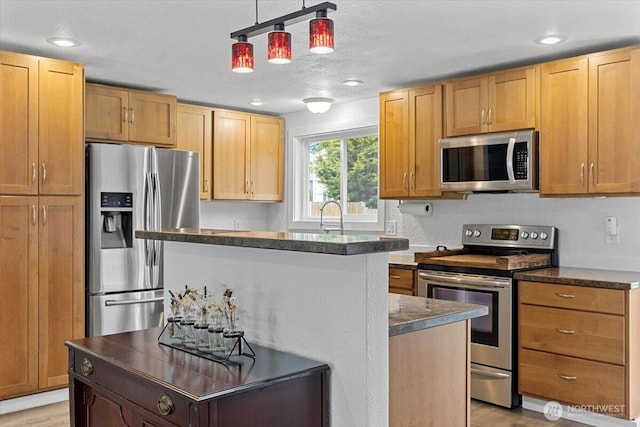 kitchen featuring a kitchen island, light wood-style flooring, a sink, stainless steel appliances, and decorative light fixtures