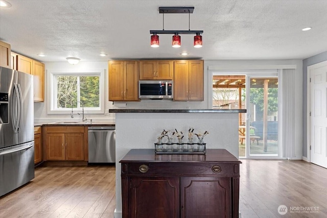 kitchen with dark countertops, a textured ceiling, recessed lighting, light wood-style floors, and appliances with stainless steel finishes