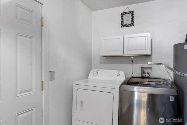 laundry area featuring water heater, washing machine and dryer, and cabinet space