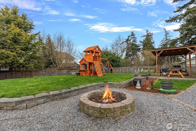 view of yard featuring an outdoor fire pit, a playground, and a fenced backyard