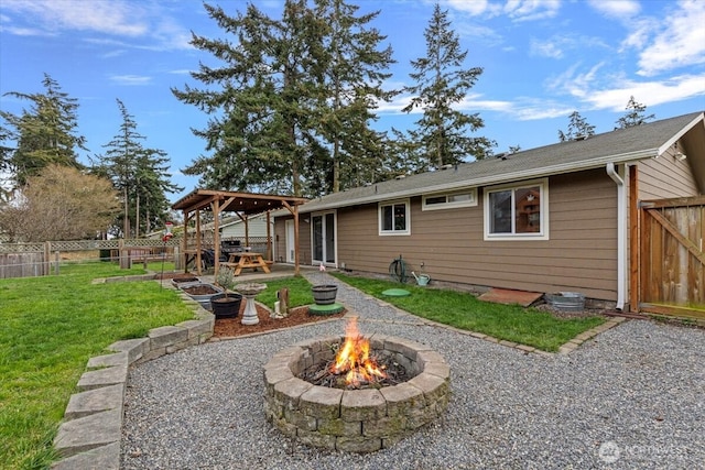 back of property with fence, a vegetable garden, a yard, a fire pit, and a patio area