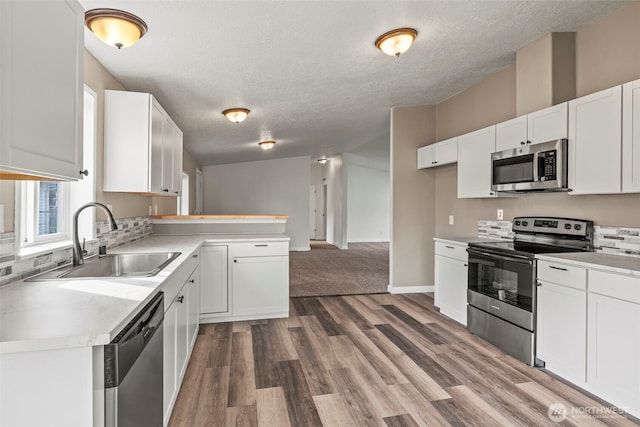 kitchen featuring white cabinetry, light countertops, appliances with stainless steel finishes, and a sink