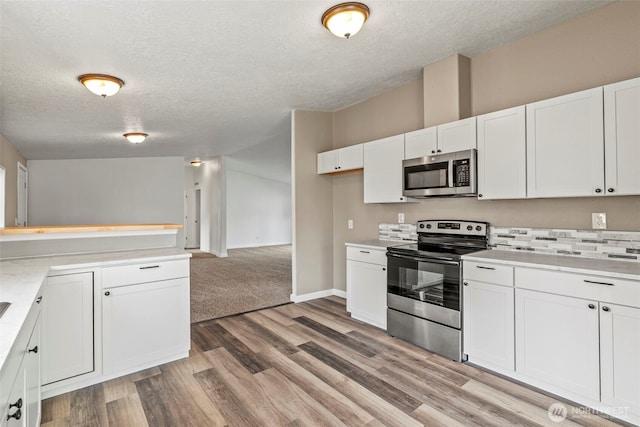 kitchen featuring a textured ceiling, appliances with stainless steel finishes, white cabinets, light wood finished floors, and light countertops