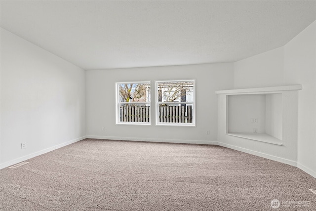 carpeted spare room featuring visible vents and baseboards