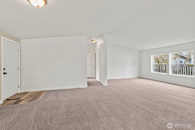 unfurnished living room featuring baseboards, a textured ceiling, and carpet