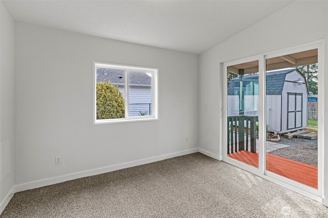 carpeted spare room with vaulted ceiling and baseboards