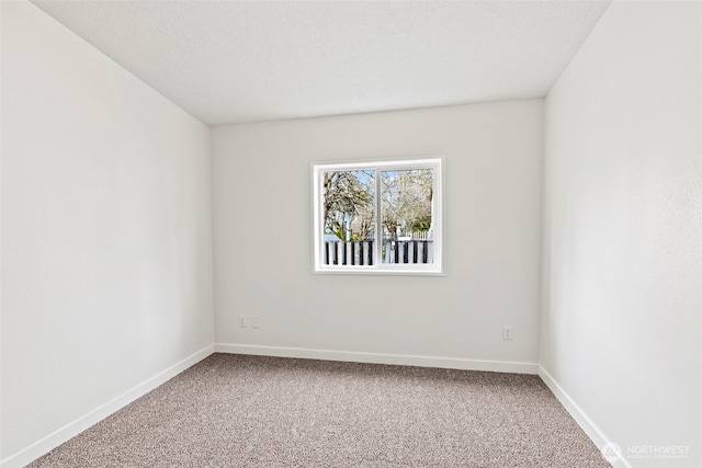 carpeted empty room with a textured ceiling and baseboards