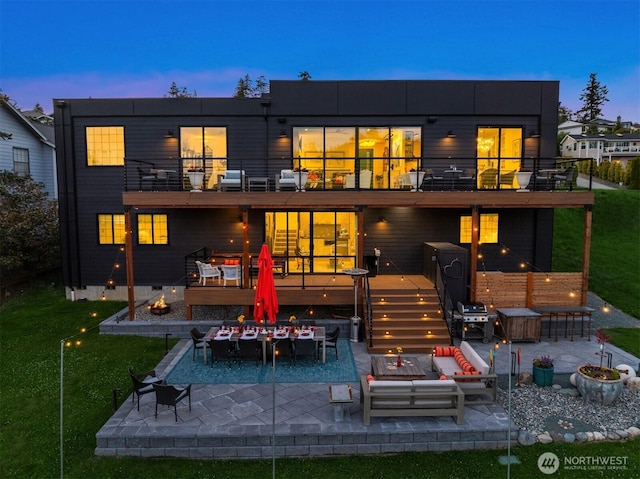 back of property at dusk featuring an outdoor living space, a yard, outdoor dining area, a balcony, and a patio area