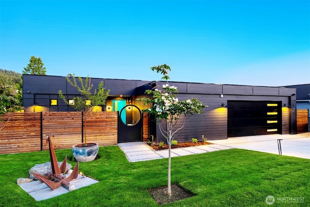 view of front of home featuring a front yard, fence, a garage, and driveway