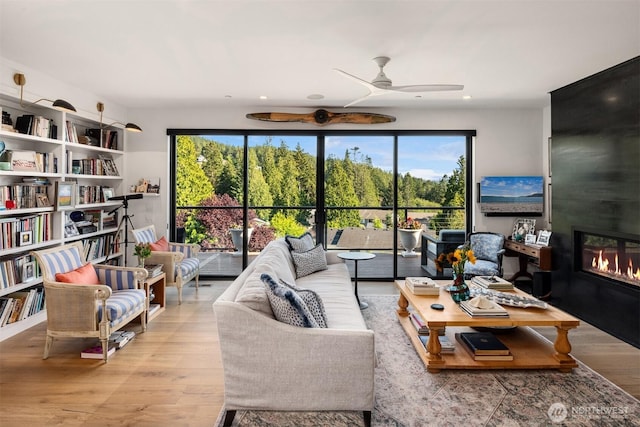 living area with wood finished floors, recessed lighting, a fireplace, and ceiling fan