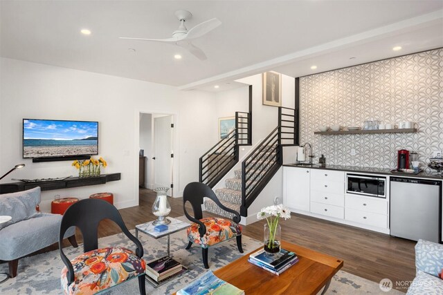 living area featuring ceiling fan, stairway, indoor wet bar, recessed lighting, and dark wood-style floors