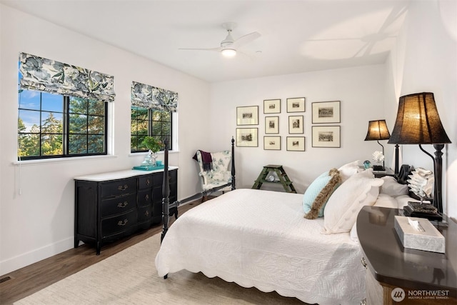 bedroom with ceiling fan, baseboards, multiple windows, and wood finished floors