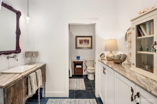 bathroom featuring baseboards, toilet, vanity, and tile patterned flooring