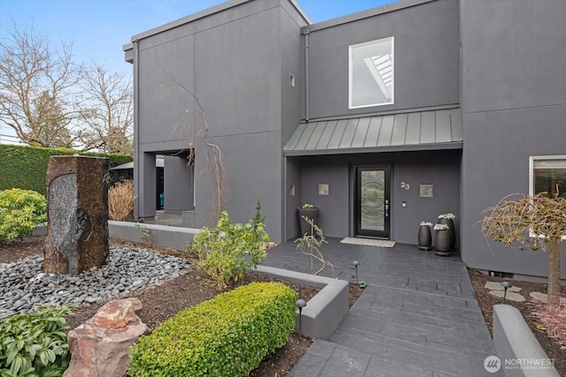 view of front of home featuring stucco siding, metal roof, and a standing seam roof