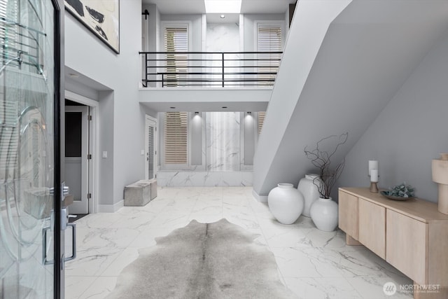 entrance foyer with marble finish floor, a high ceiling, and baseboards