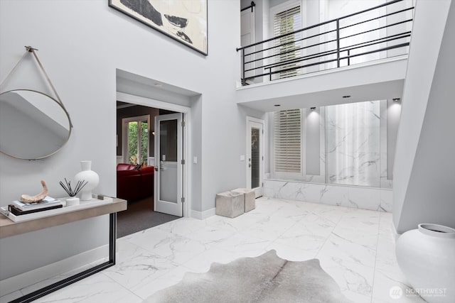 interior space featuring french doors, a high ceiling, marble finish floor, and a healthy amount of sunlight