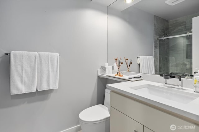 bathroom with a shower stall, toilet, vanity, and baseboards