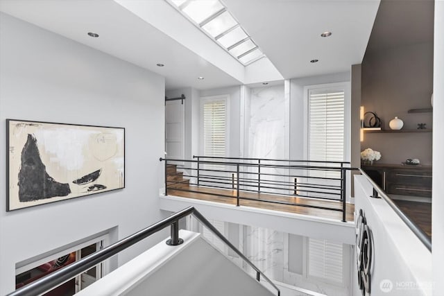 stairway featuring a barn door, a skylight, and recessed lighting