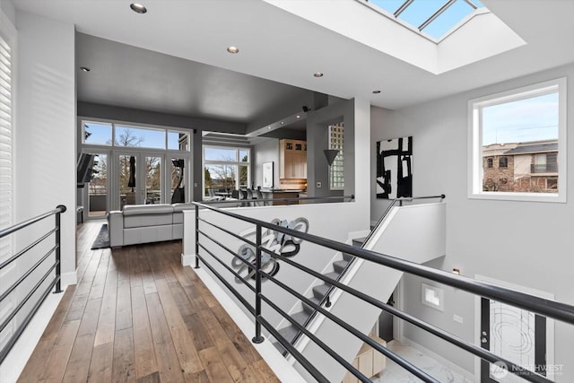 hallway featuring hardwood / wood-style floors, an upstairs landing, a skylight, and recessed lighting