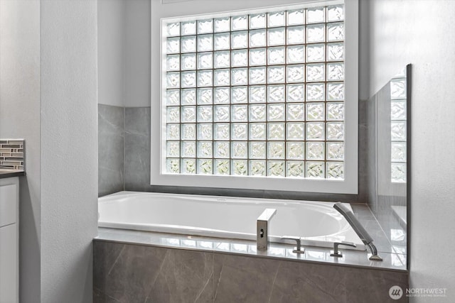 bathroom featuring a garden tub and a textured wall