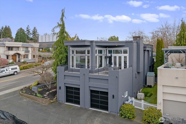 view of front of property featuring aphalt driveway, a balcony, an attached garage, and fence