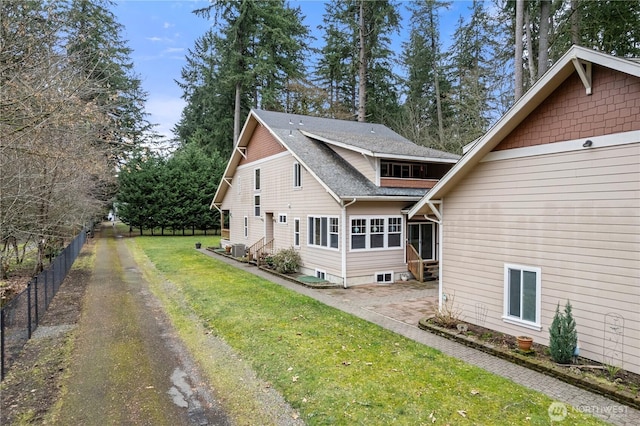 rear view of house featuring fence, entry steps, roof with shingles, cooling unit, and a yard