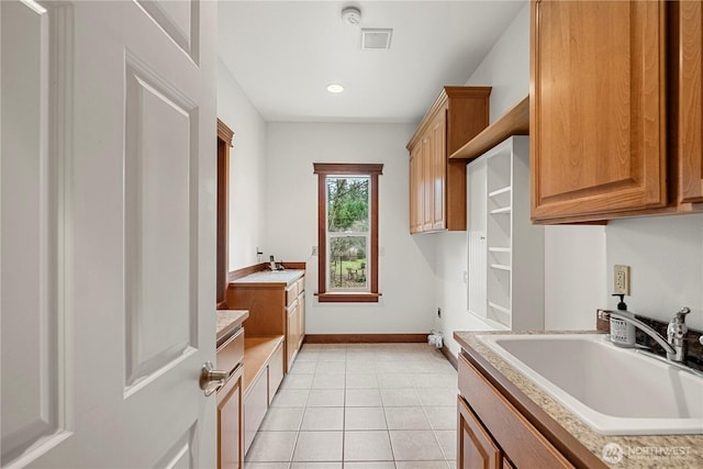 clothes washing area featuring visible vents, baseboards, light tile patterned floors, cabinet space, and a sink