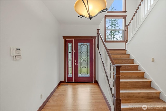 entrance foyer featuring stairs, light wood-style floors, and baseboards