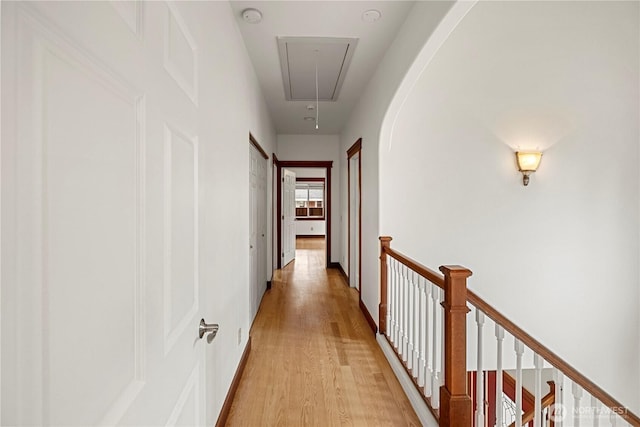 corridor with attic access, an upstairs landing, light wood-type flooring, and baseboards